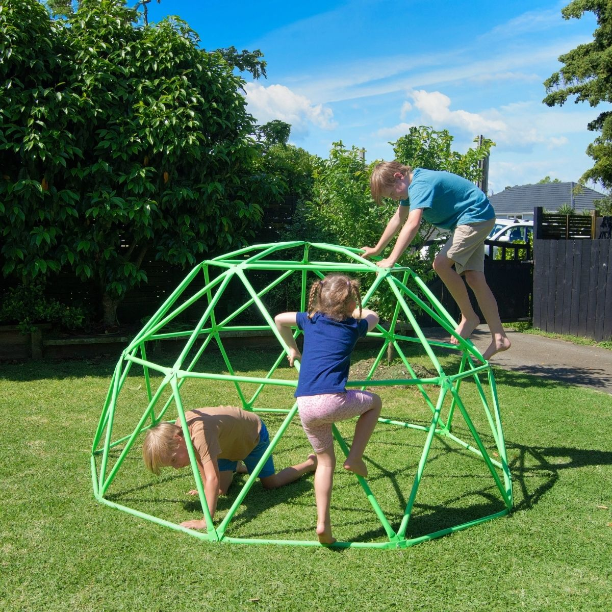 Three young kids climbing dome climber in garden.